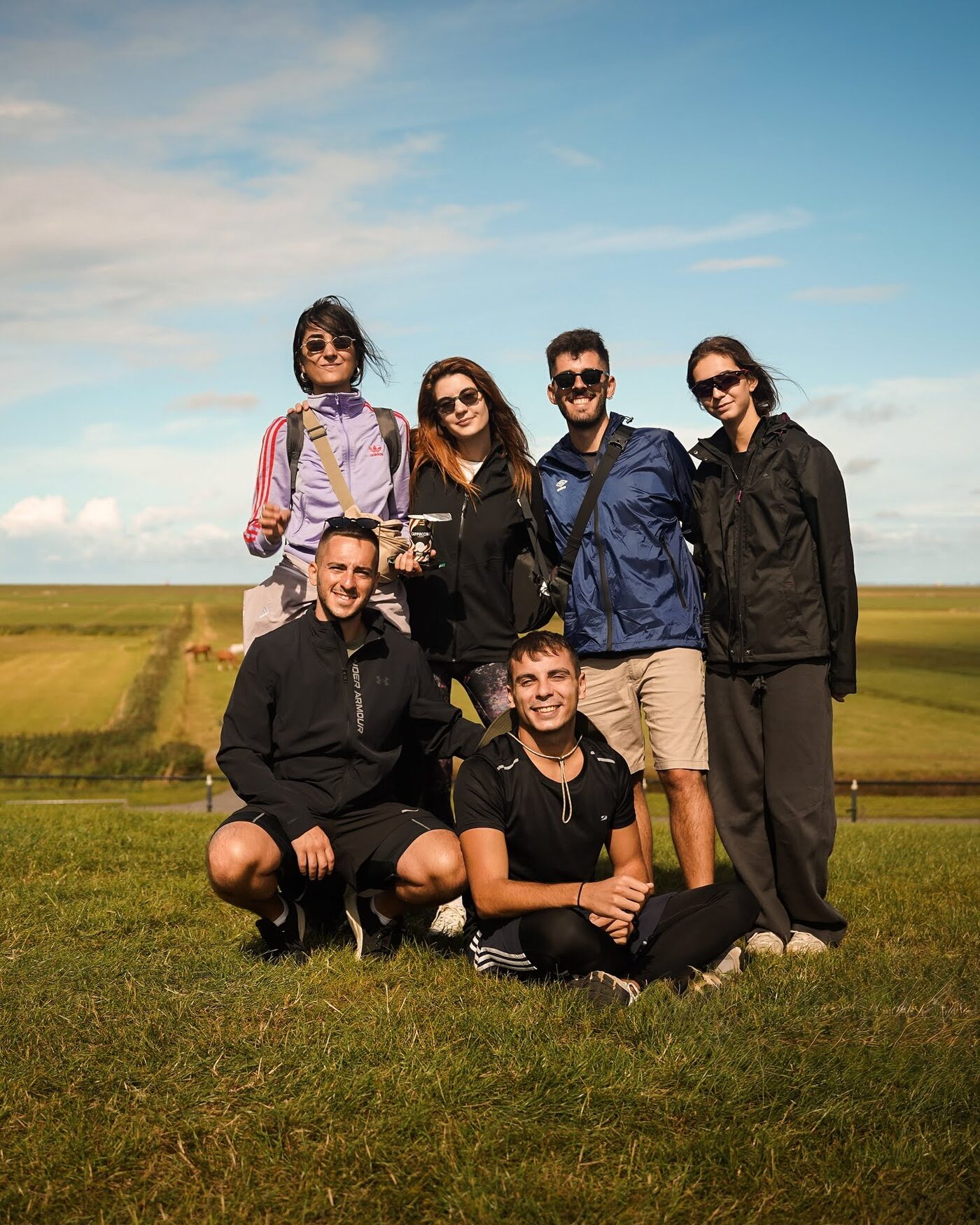 Participants crouching and smiling on a grass dike