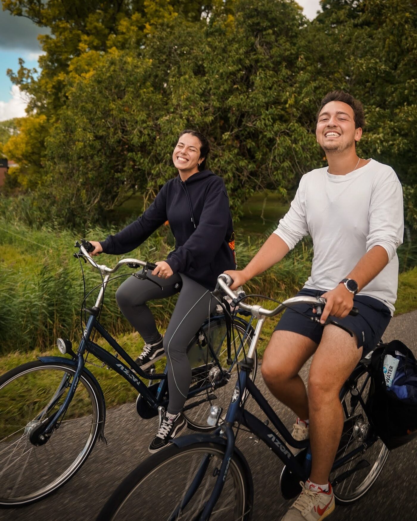 Two participants smiling as they cycle along a country path