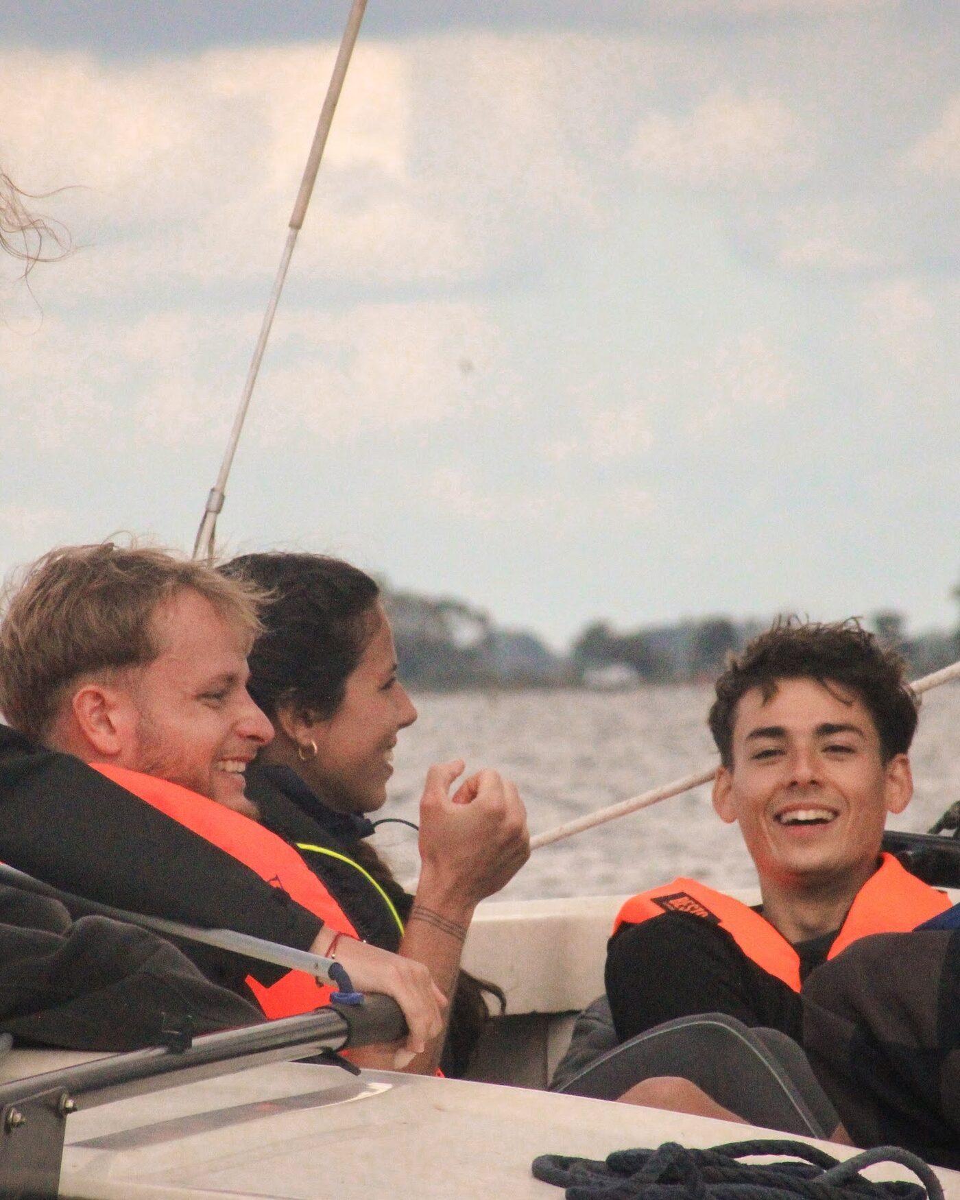 Participants laughing in life jackets on a sailing boat