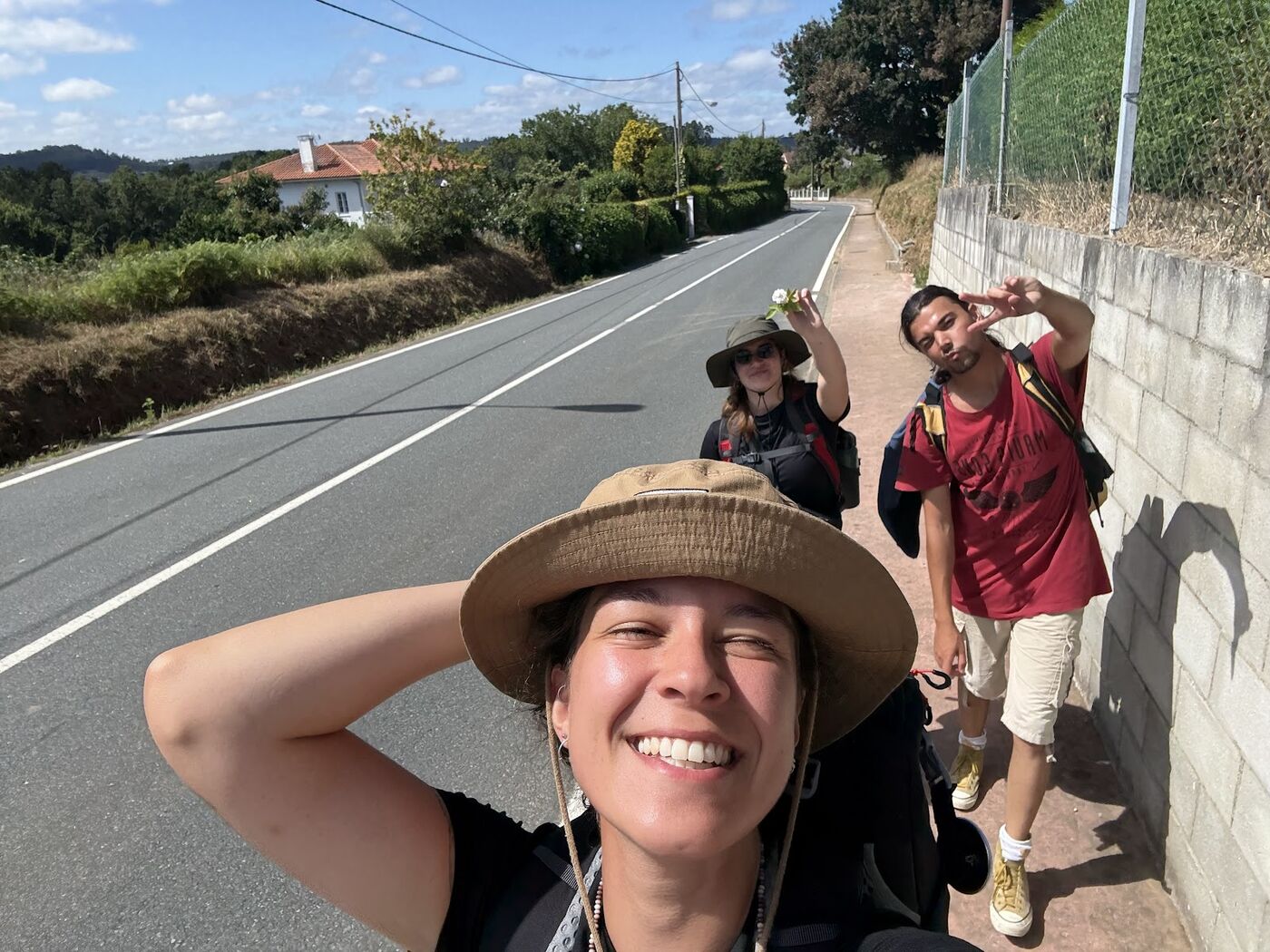 A smiling walker in a sun hat taking a selfie on the road