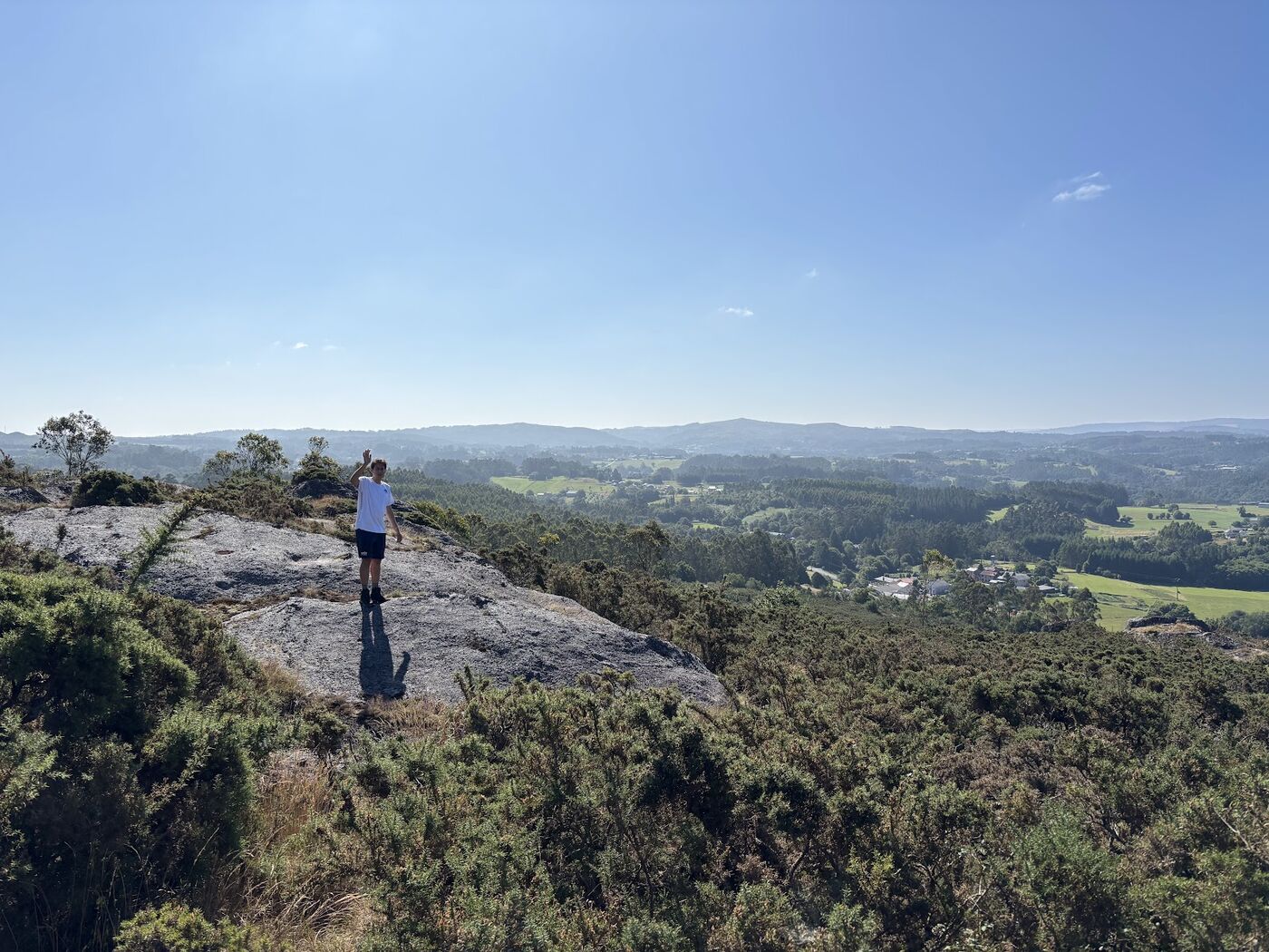 A walker standing on a rock above a Galician landscape