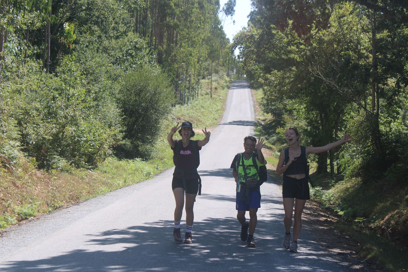 Walkers raising their arms on a tree lined road